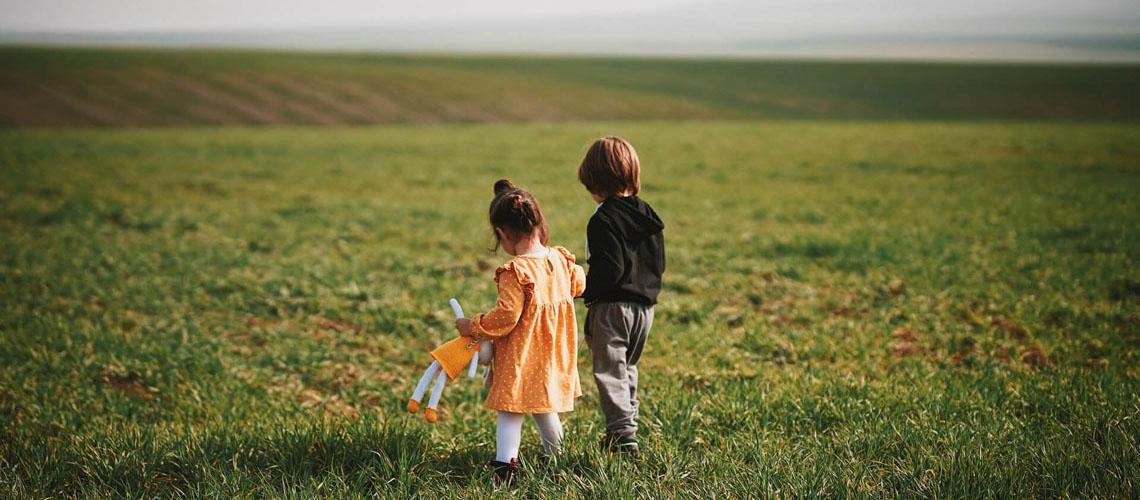 Foto på två barn i ett fält